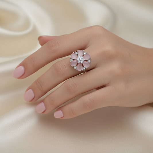 Hand wearing a pink floral ring on a soft beige background